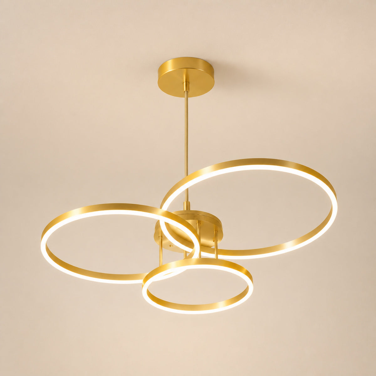Plafonnier 3 anneaux LED dorés, sur fond neutre